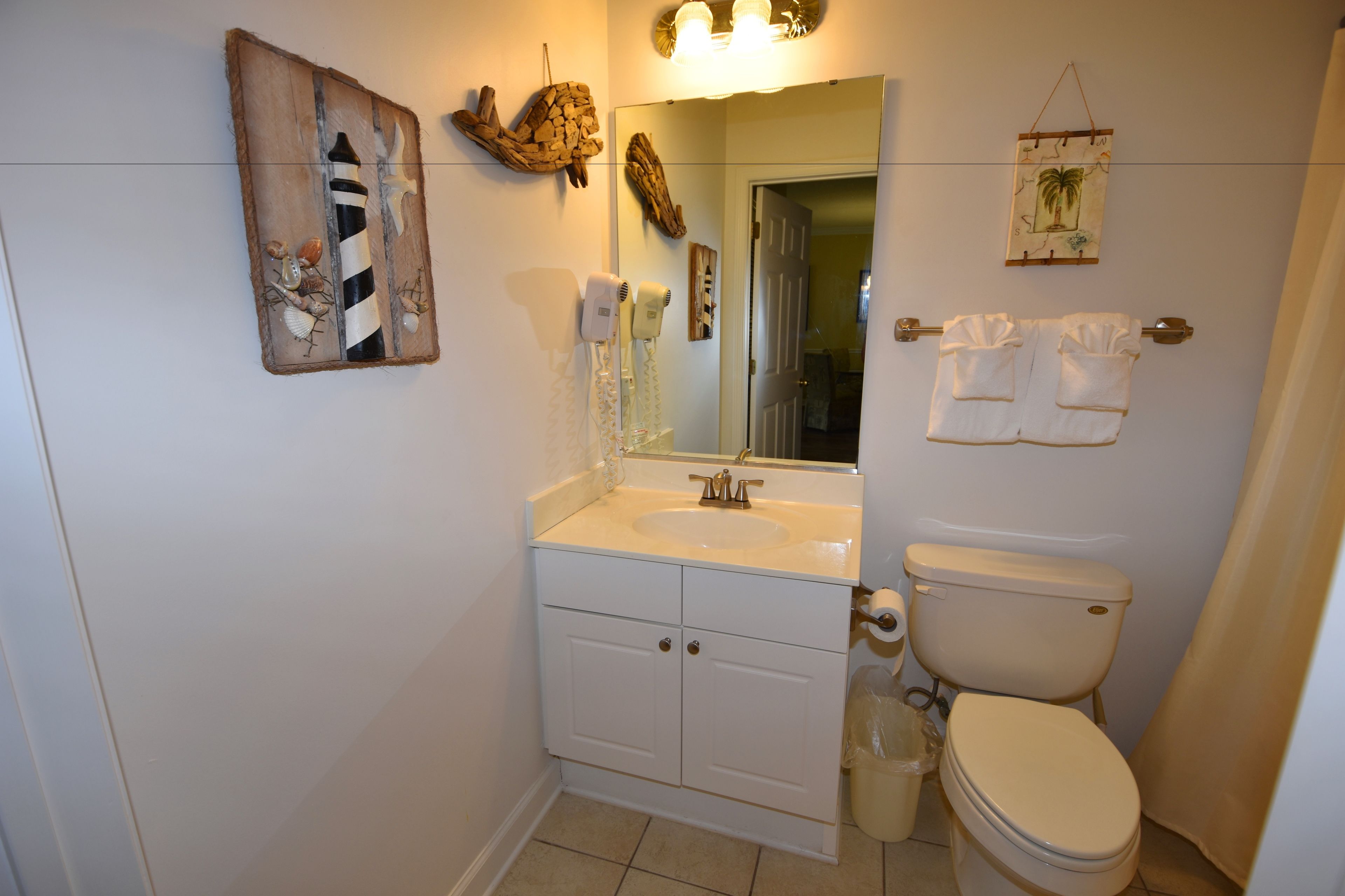 Un baño con lavamanos, espejo, inodoro y decoración en la pared.