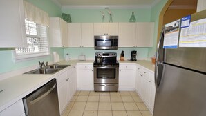 A kitchen with white cabinets, a stainless steel refrigerator, a microwave, an oven, and a dishwasher. - River Crossing Apartment 312 (North Myrtle Beach)