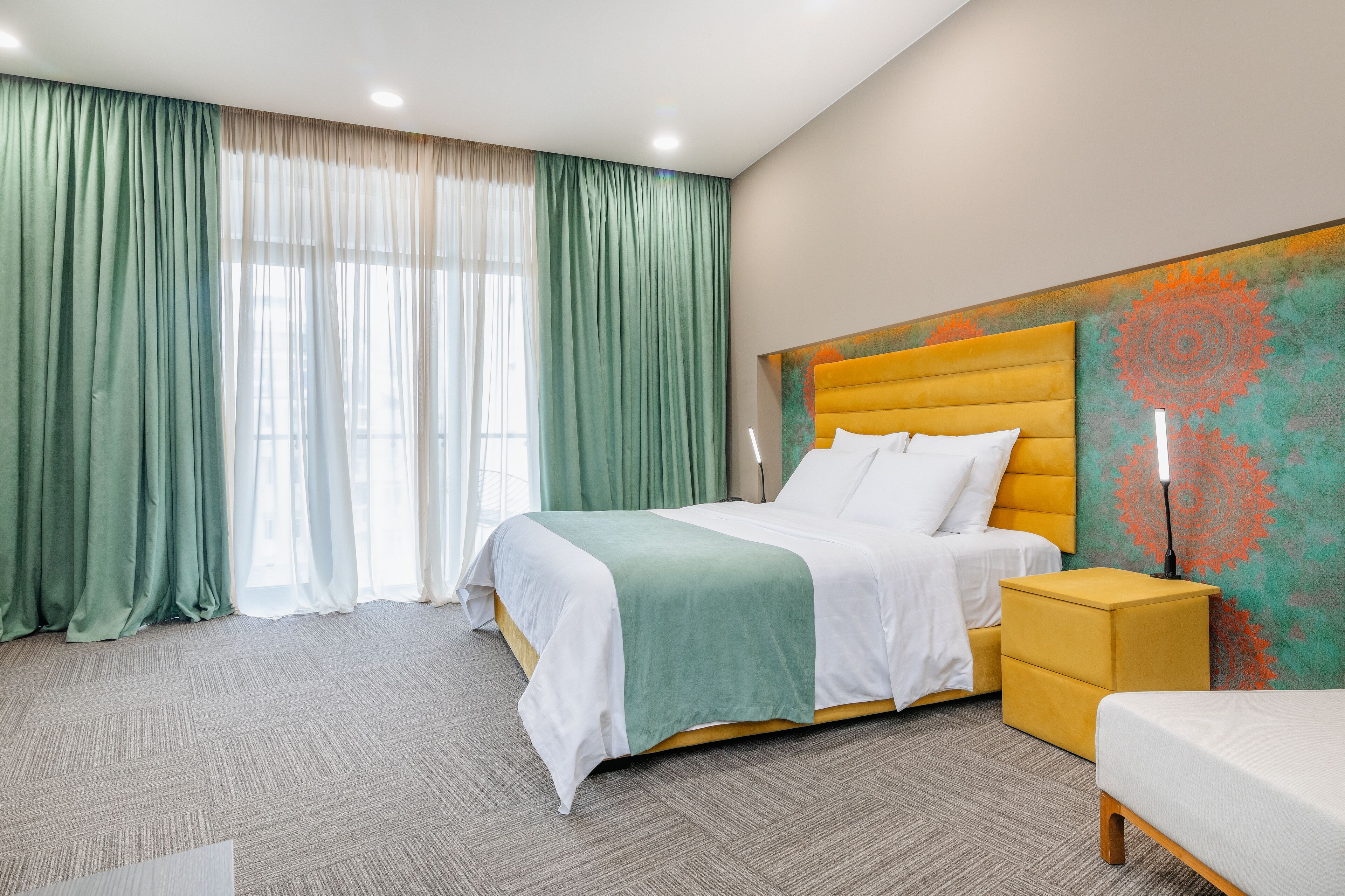 A hotel room with a large bed, a bedside table, a nightstand, and a headboard with a decorative panel.