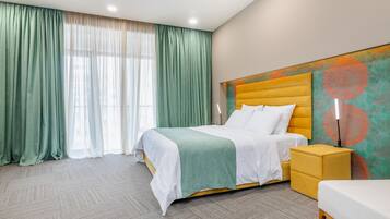 A hotel room with a large bed, a bedside table, a nightstand, and a headboard with a decorative panel.