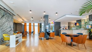 Un hall d’hôtel moderne avec un plancher en bois, un comptoir d’accueil et un espace bar.