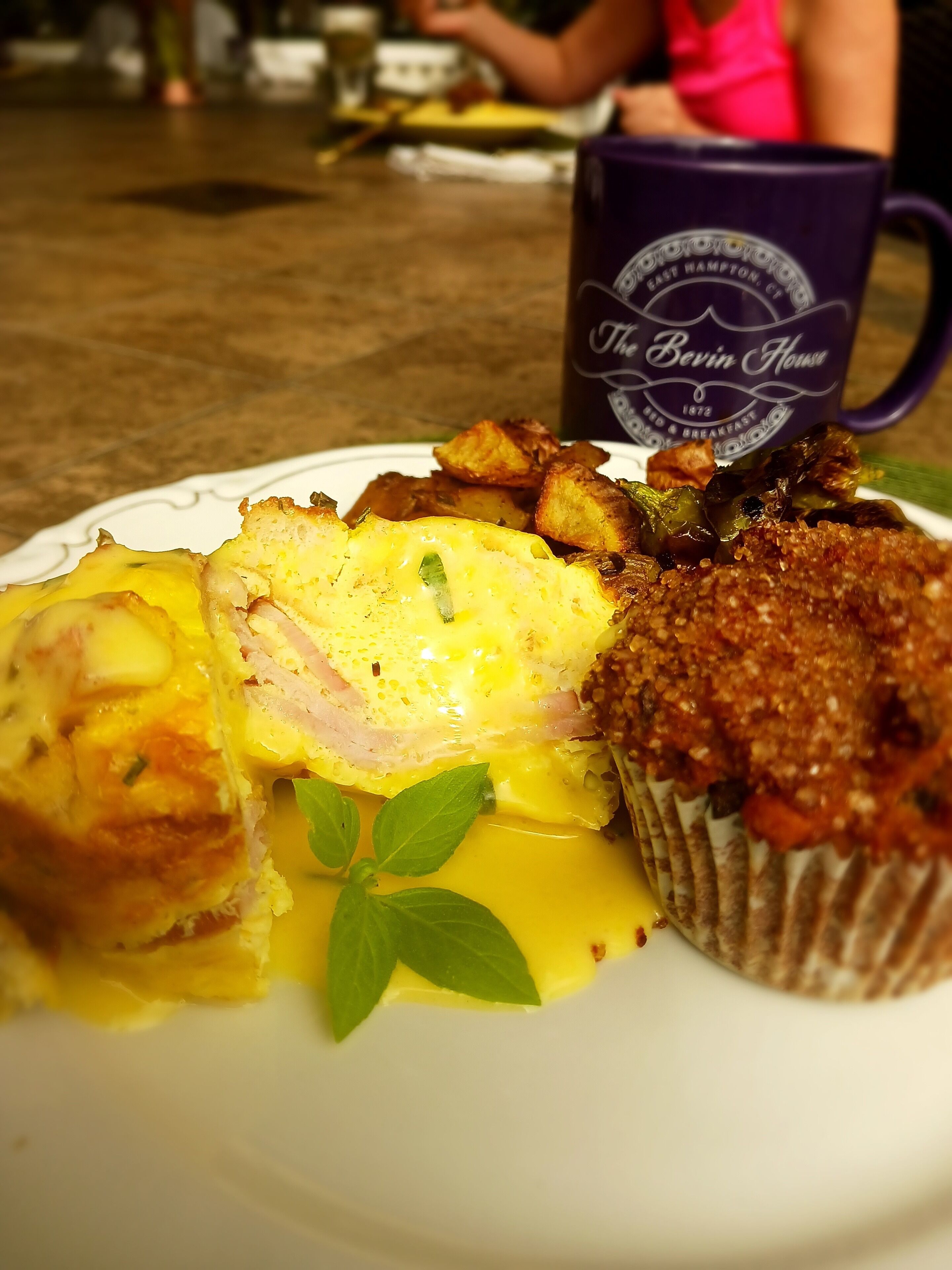 A plate of food with a muffin, hash browns, and a slice of egg.