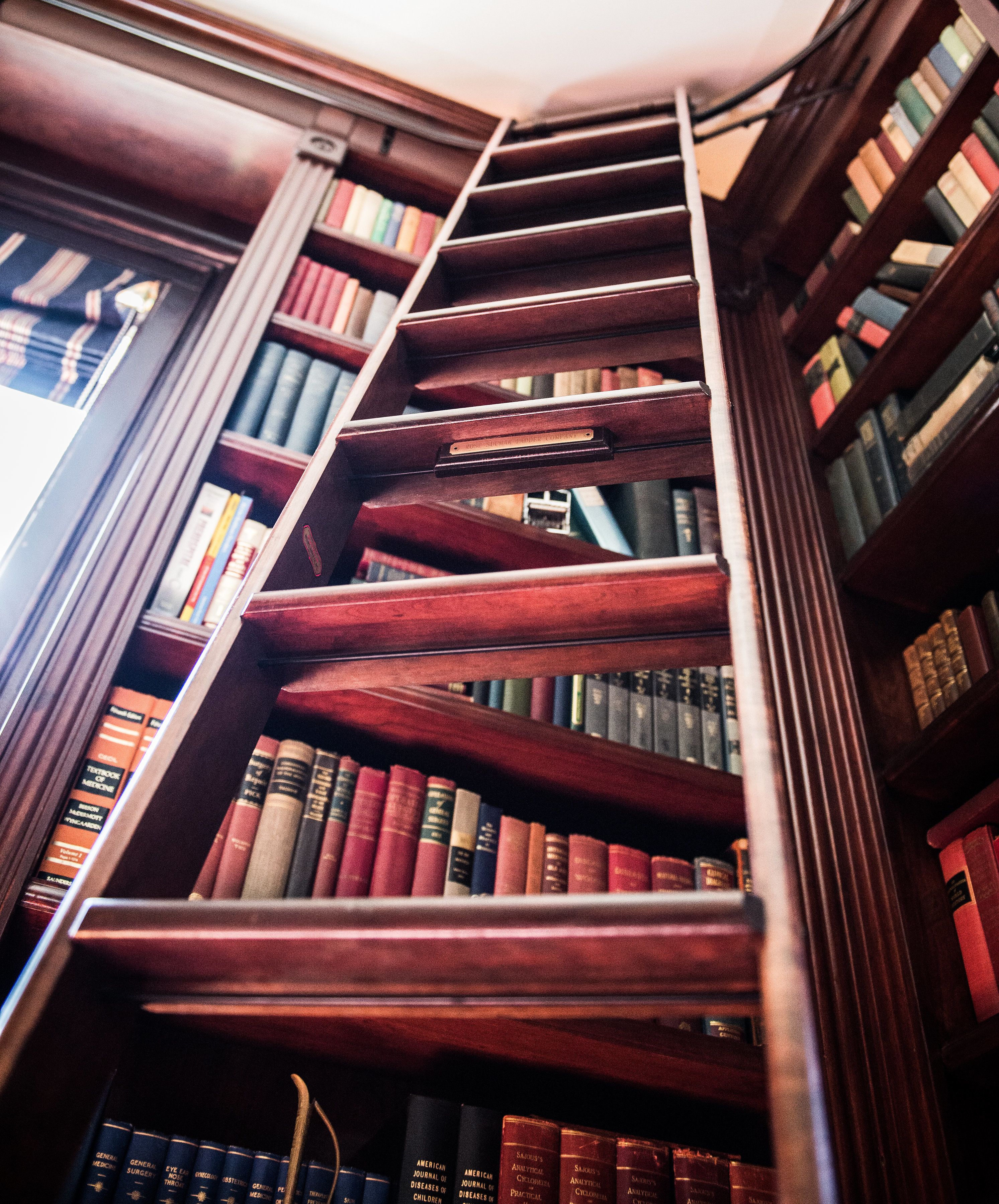A wooden staircase in a library with bookshelves on either side.