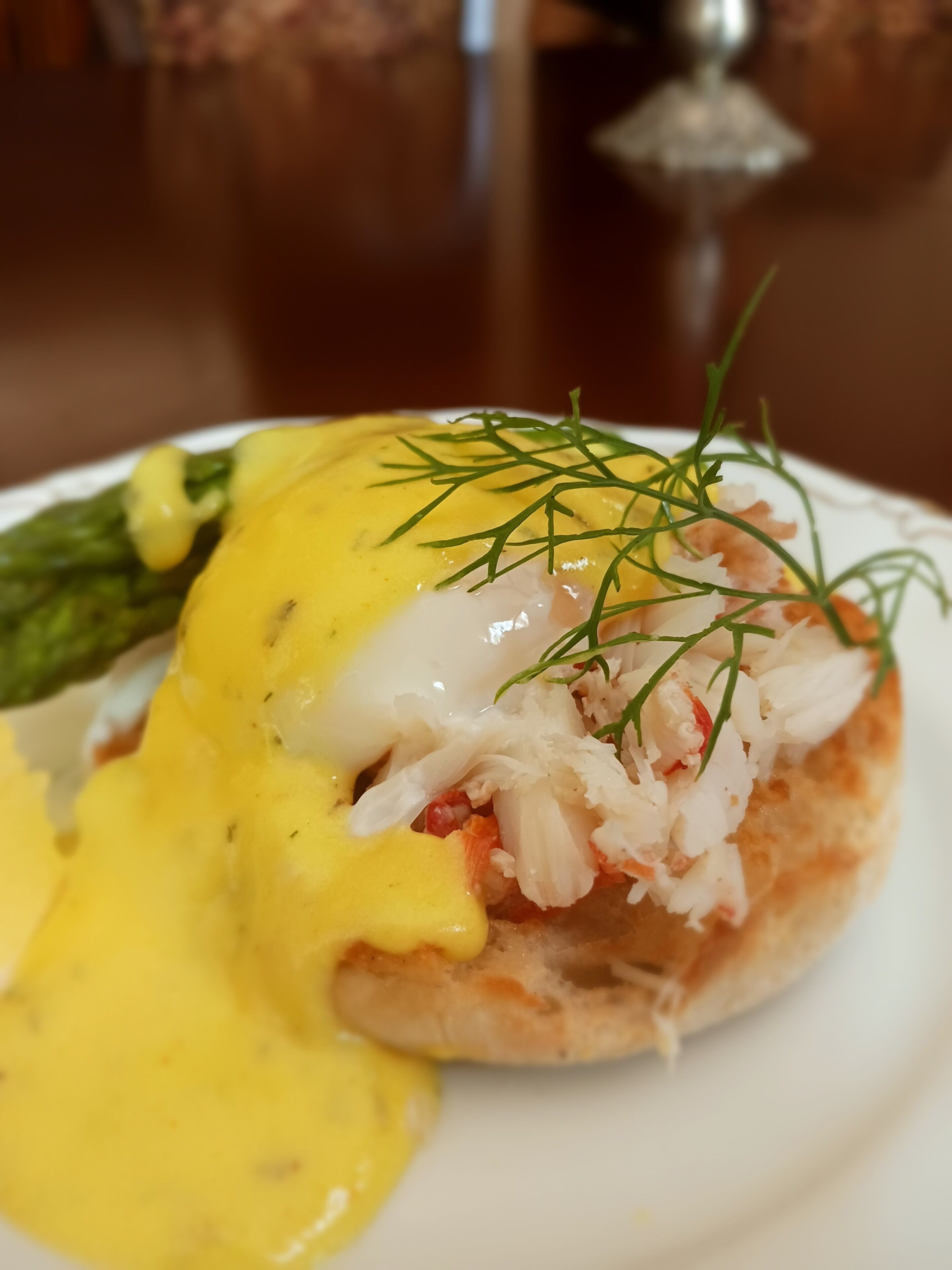 A plate with a seafood dish, possibly a lobster roll, topped with a creamy sauce and garnished with dill.