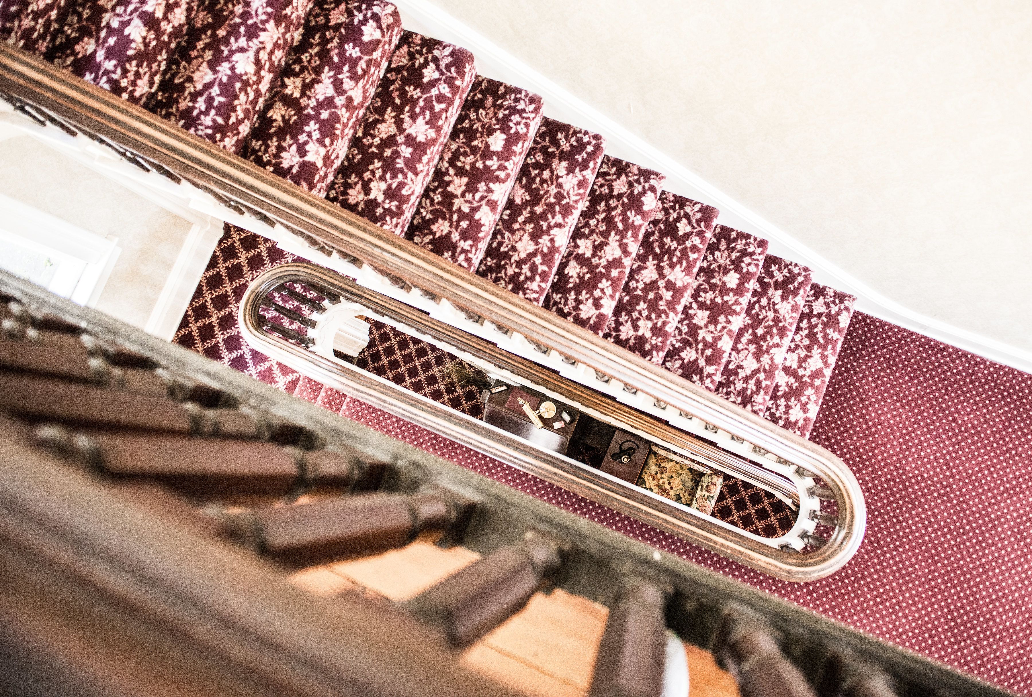 A staircase with patterned carpet and a metal railing.
