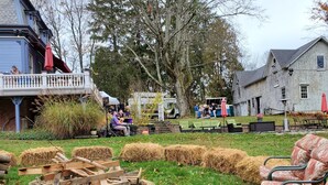 A rustic outdoor setting with hay bales, a wooden fire pit, and outdoor seating. - The Bevin House Bed & Breakfast (East Hampton)