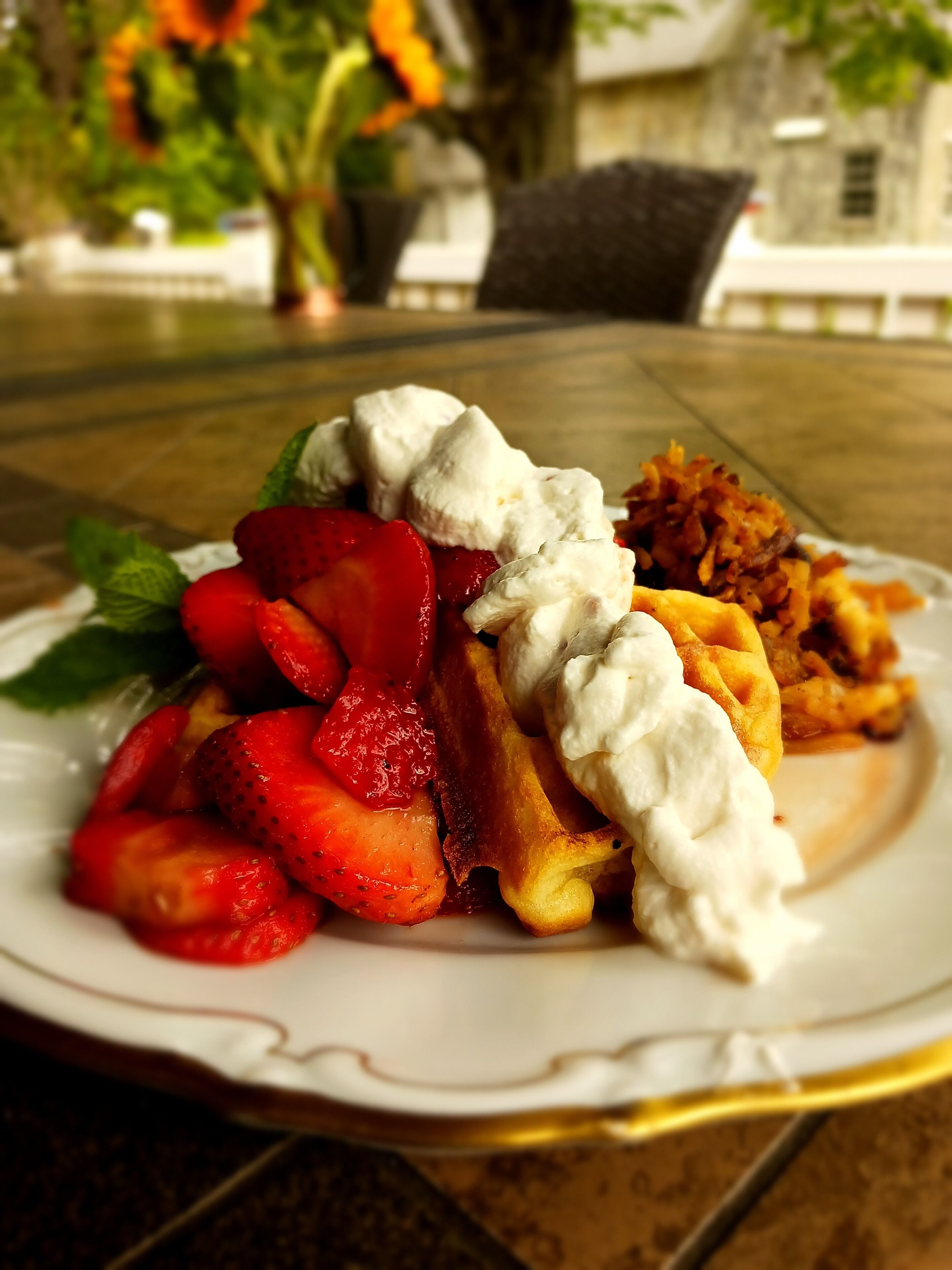 A plate of food with waffles, strawberries, and whipped cream.