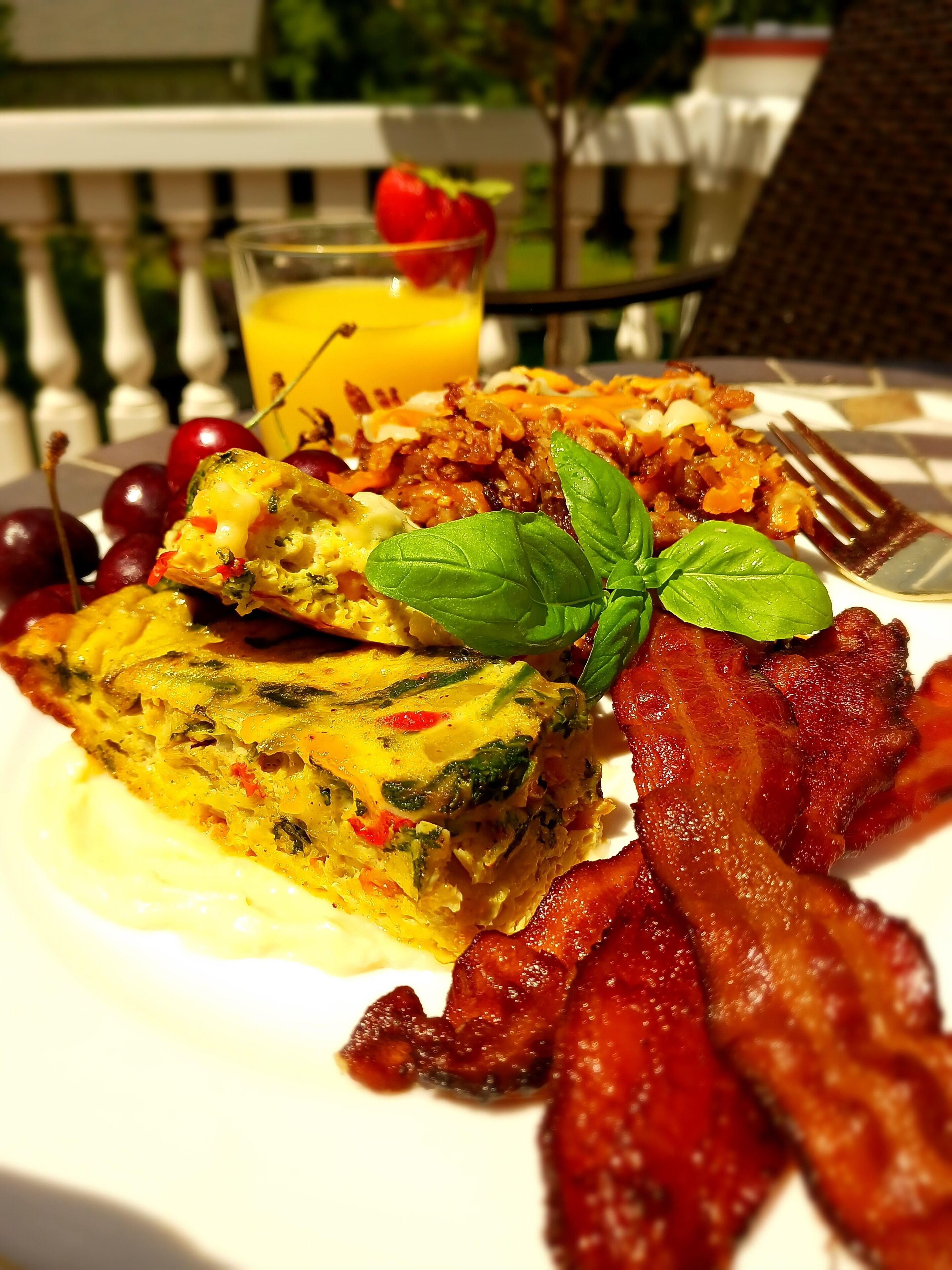 Un plato de desayuno con huevos, tocino y tomates cherry.