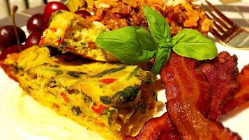 Un plato de desayuno con huevos, tocino y tomates cherry.