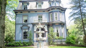 A large, blue Victorian-style house with a prominent fountain in the front yard. - The Bevin House Bed & Breakfast (East Hampton)