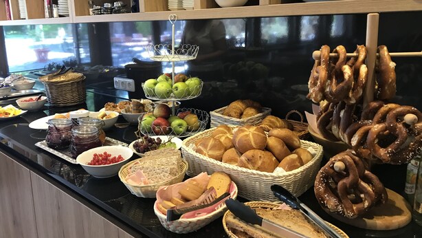 Een buffet met diverse gerechten, waaronder fruit, brood en gebak.