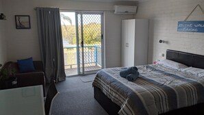 Une chambre à coucher avec un lit, un ventilateur de plafond, une fenêtre avec des rideaux et un panneau accroché au mur.