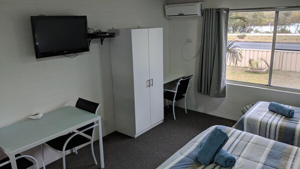 Une chambre avec un lit, un bureau, une chaise, une armoire et un téléviseur.