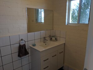 Un baño con lavabo blanco, espejo y paredes con azulejos.