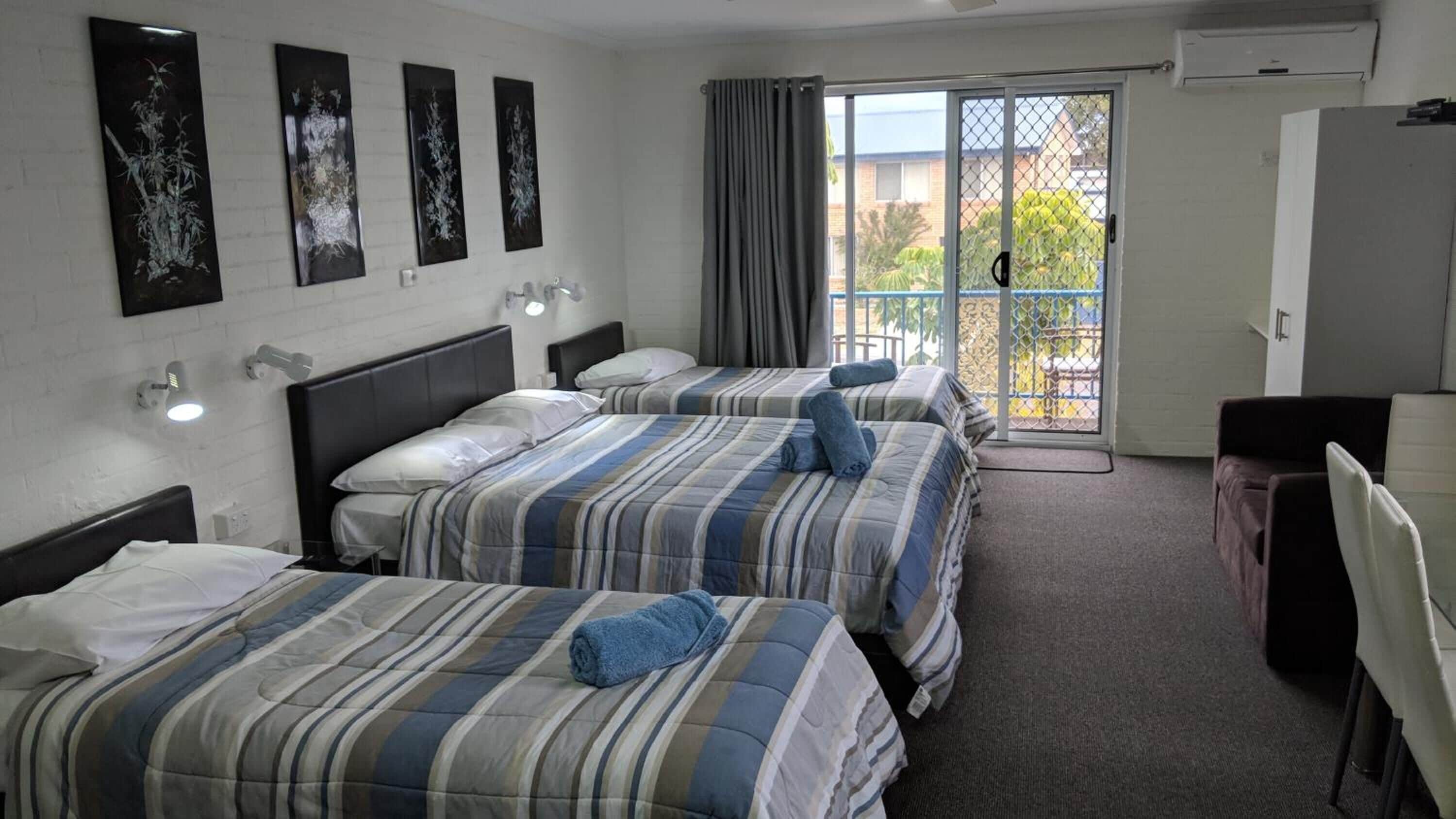 Habitación de hotel con dos camas, un escritorio y una silla. Hay luces fijadas a la pared y una ventana con cortinas.