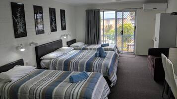 Habitación de hotel con dos camas, un escritorio y una silla. Hay luces fijadas a la pared y una ventana con cortinas.