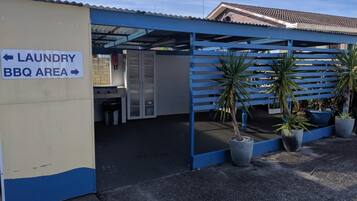 Un espacio al aire libre techado con un letrero que indica zona de lavandería y barbacoa.