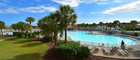 A swimming pool with a fenced area, surrounded by palm trees and grass.