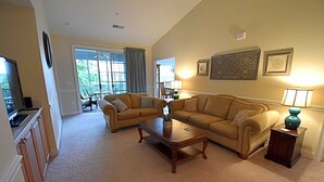 A living room with a sofa, armchairs, a coffee table, and a TV.
