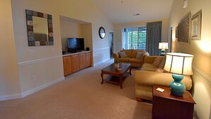 A living room with a television, sofa, coffee table, and a ceiling fan.