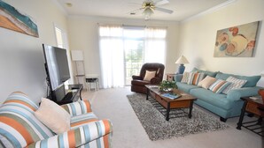 A living room with striped sofas, a coffee table, a TV, and a ceiling fan.