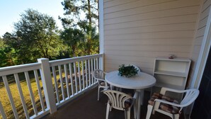 A covered patio with a white railing, a round table, and two chairs.