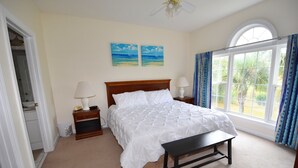 A bedroom with a bed, a bench, a nightstand, a window with curtains, and two paintings on the wall.