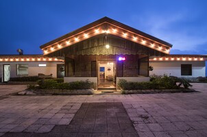 Um edifício com fachada de pedra, entrada de madeira e letreiro de neon.