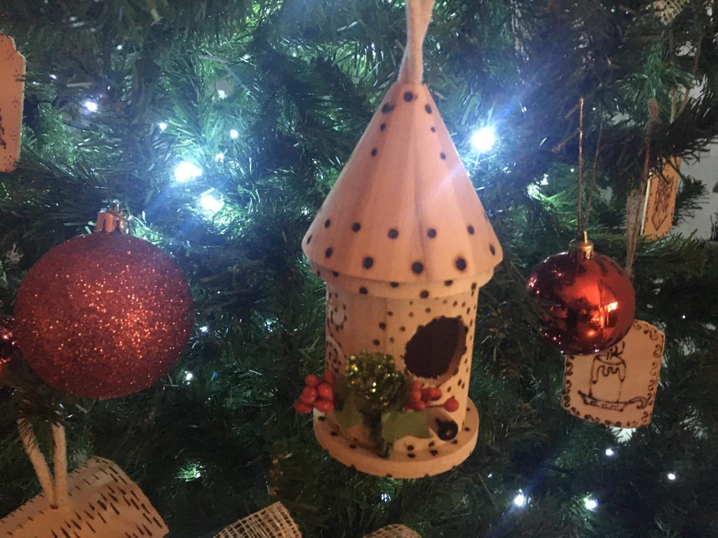 Árvore de Natal decorada com vários enfeites, incluindo uma bola vermelha brilhante, um enfeite cônico com manchas pretas e uma esfera vermelha.