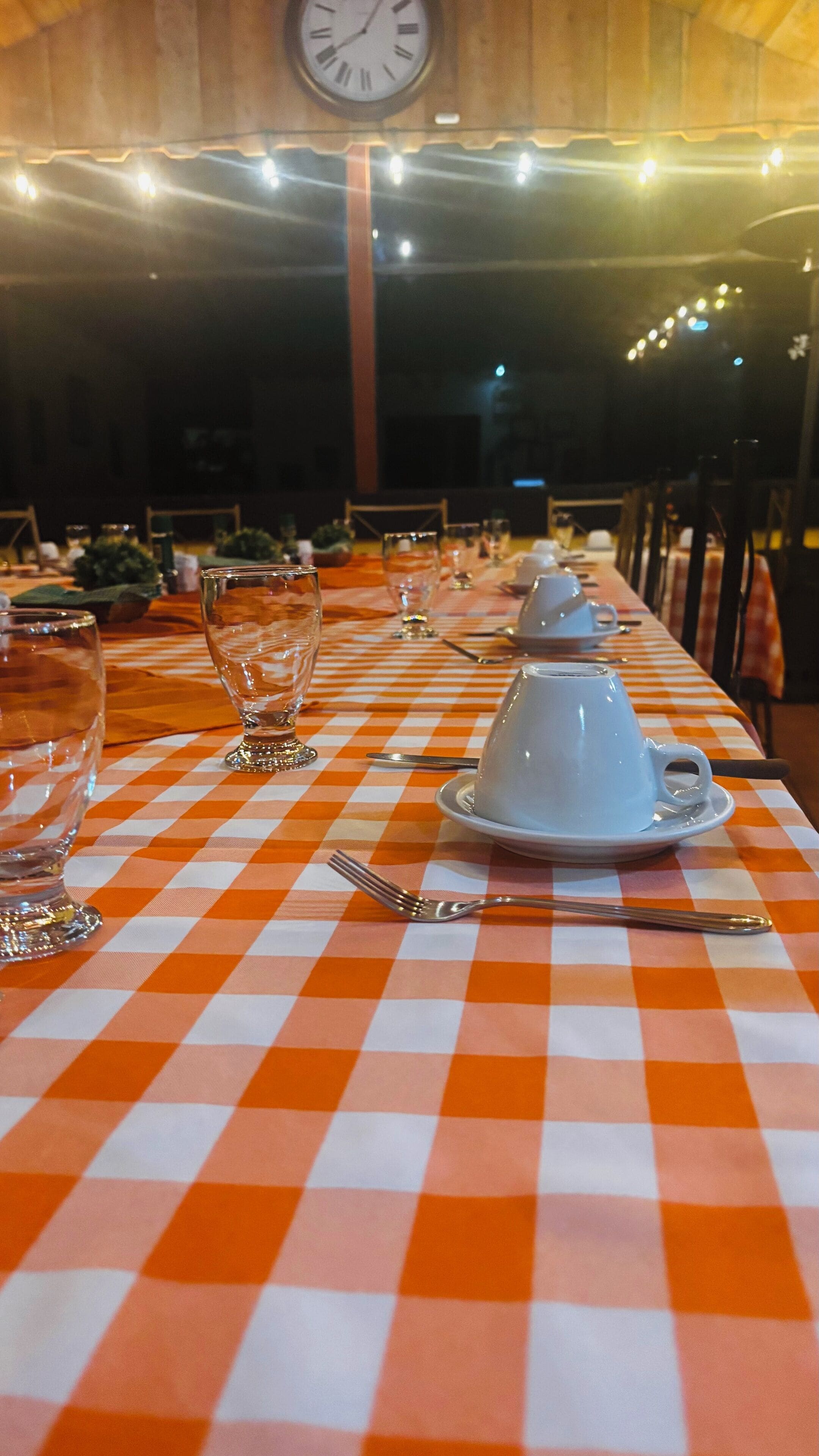 Una mesa de comedor con mantel a cuadros, vasos y cubiertos.