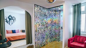 Een moderne hotelkamer met een bed, een rode bank en een wand bekleed met reflecterende tegels.