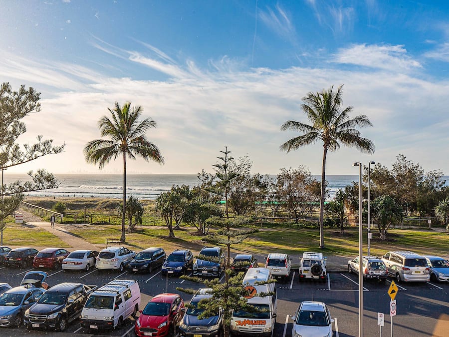 A parking lot with various cars and a view of the ocean in the background.