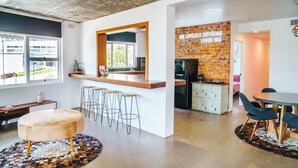 Een moderne keuken met een accentmuur van baksteen, een bar en een eethoek met krukken.