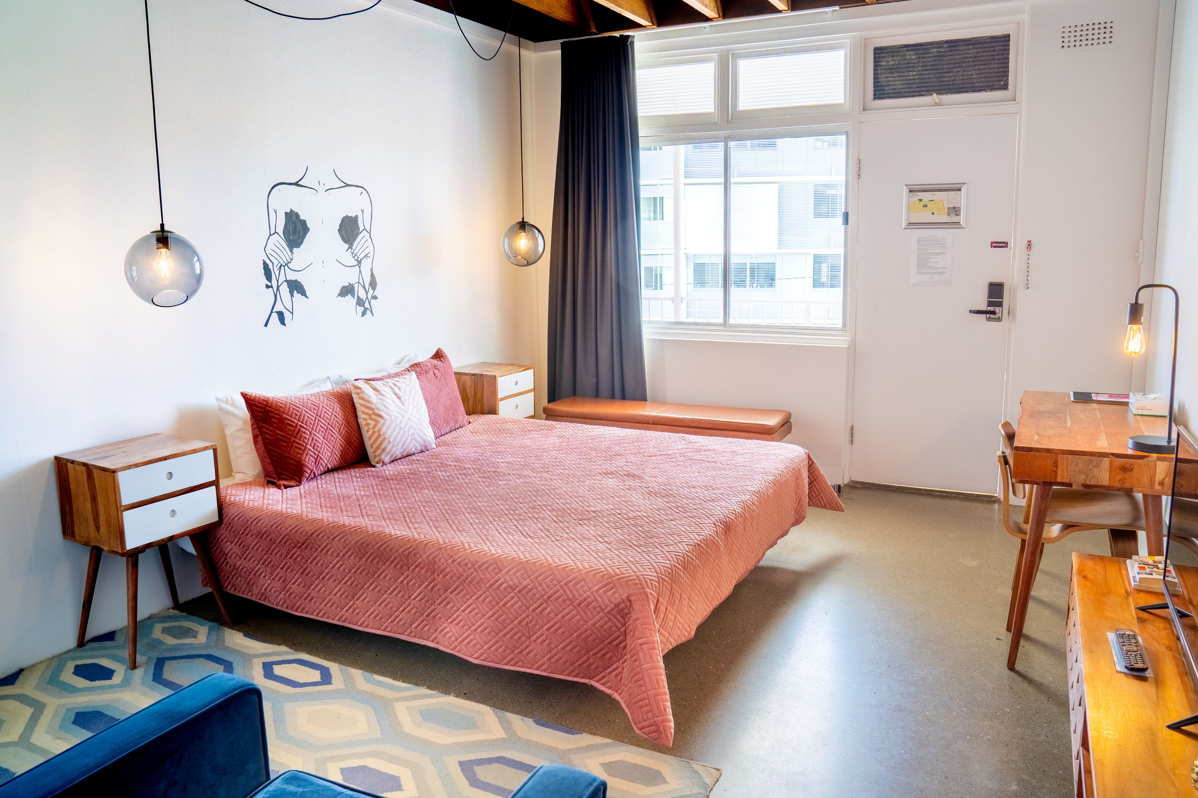 A bedroom with a bed, bedside tables, a desk, and a chair.