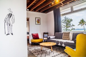 Una sala de estar moderna con sofá, sillón amarillo y una mesa de centro redonda de madera.
