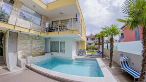 Un edificio de dos pisos con piscina, asientos exteriores y un balcón.