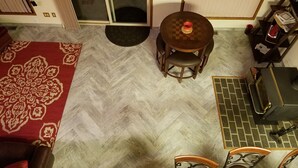 A room with a herringbone patterned floor, a round wooden table with chairs, a red patterned rug, a sliding glass door, and a small kitchen area with a stove. - Forks & twilighters getaway at the edge of SolDuc River.. bike, hike, walk, fish (Forks)