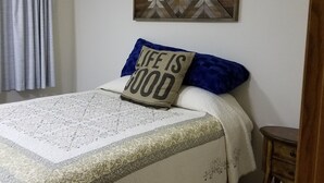 A bedroom with a bed, a wall-mounted picture, and a small wooden nightstand. - Forks & twilighters getaway at the edge of SolDuc River.. bike, hike, walk, fish (Forks)