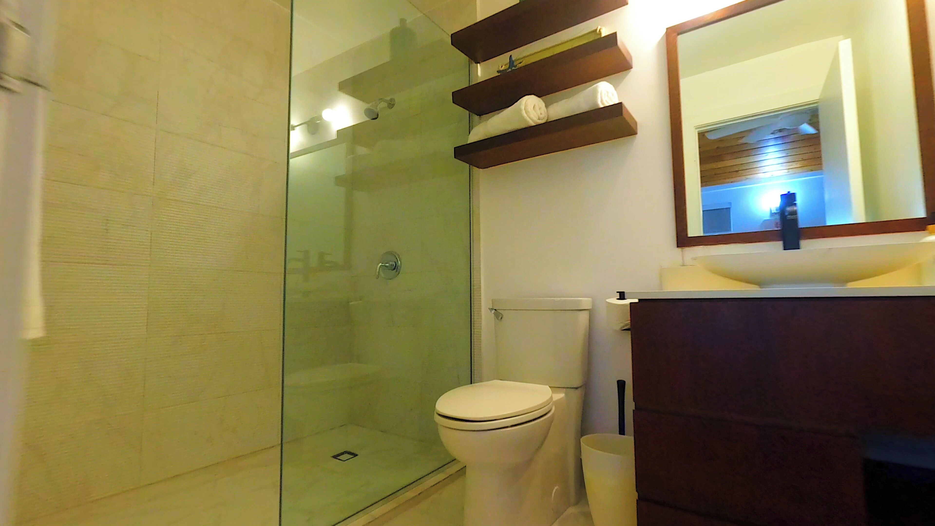 Une salle de bain moderne avec une douche à parois de verre, des toilettes et un meuble-lavabo avec un miroir.