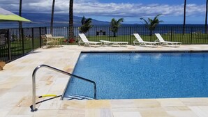 Una piscina con sillas de descanso y vistas al océano.
