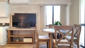 Una sala de estar moderna con una televisión de pantalla plana, muebles de madera y un amplio ventanal que ofrece luz natural.