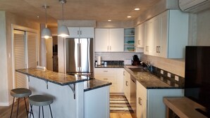 Una cocina moderna con una isla central, electrodomésticos de acero inoxidable y armarios blancos.