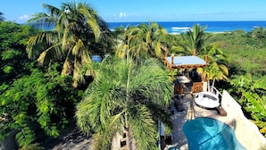 Un resort tropical con piscina, terraza de madera y vista al océano.