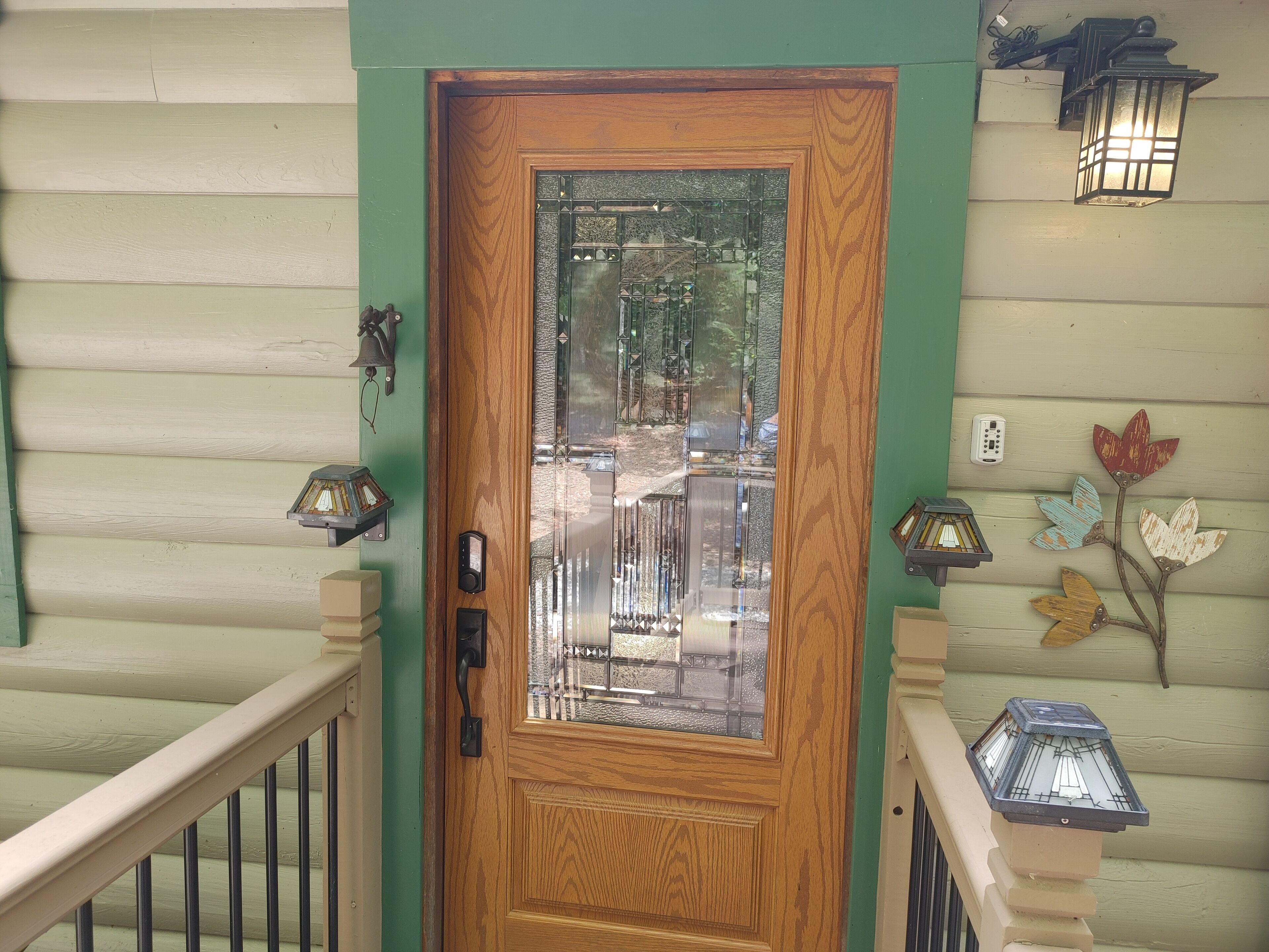 A wooden door with a glass panel, a green painted wall, and a white railing.