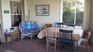 Una habitación acogedora con una mesa de comedor, sillas, un sofá y una estantería.