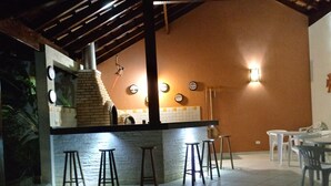 Una zona de bar con taburetes, un horno de ladrillo y piso de baldosas.