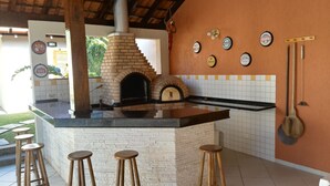 Una cocina con horno de ladrillo, taburetes y posavasos de botellas de cerveza en la pared.