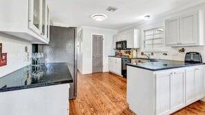 Una cocina moderna con armarios blancos, una isla central y un microondas integrado.
