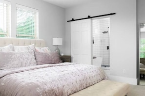 Une chambre à coucher comprenant un lit, une table de chevet, une lampe et une porte coulissante donnant sur une salle de bain.