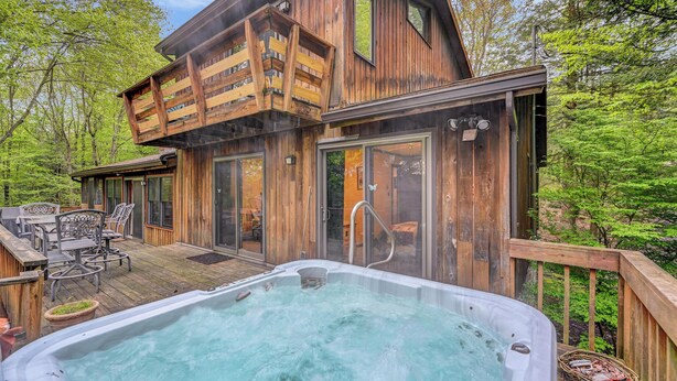 Eine Holzhütte mit Whirlpool, Terrasse und Gartenmöbeln.